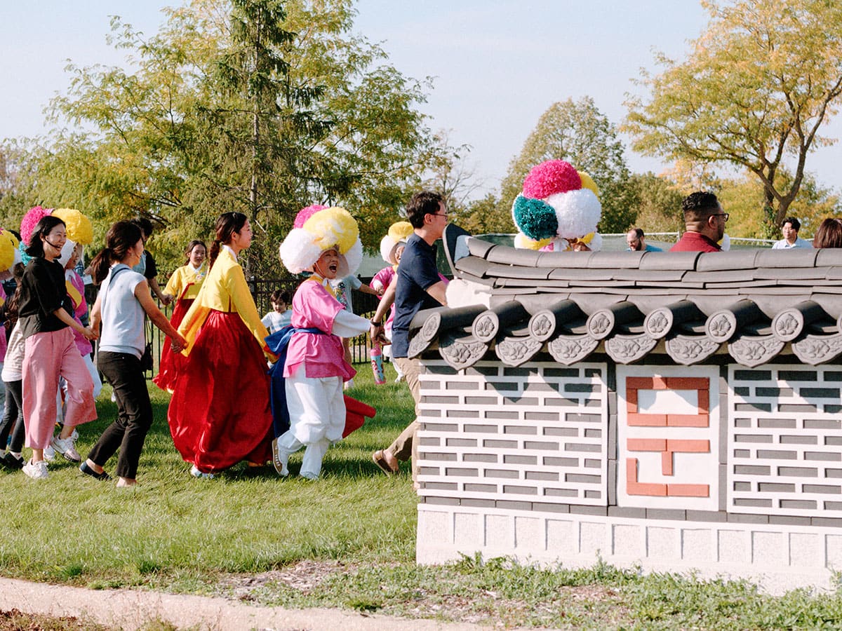 People, some in traditional costumes, hold hands and dance in a circle