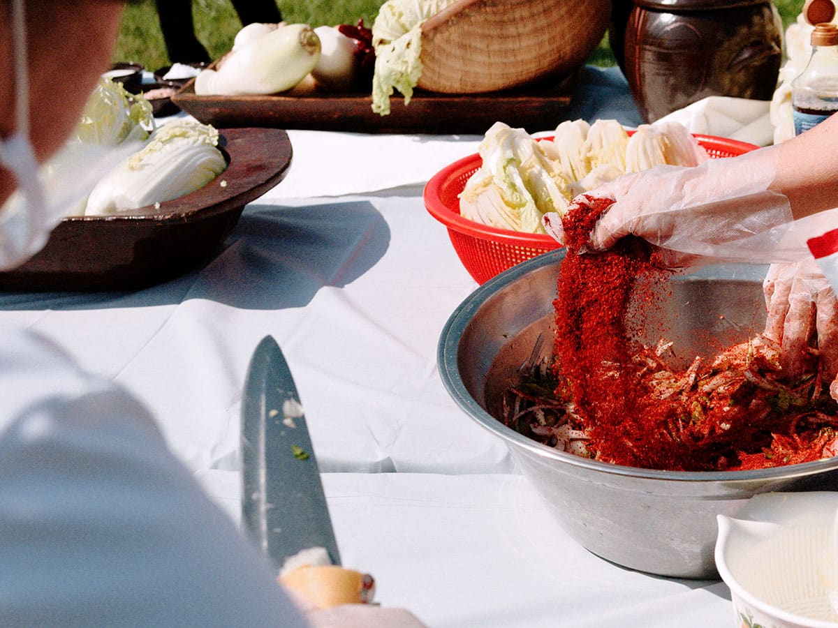 Gochugaru is sprinkled over the ingredients in a bowl