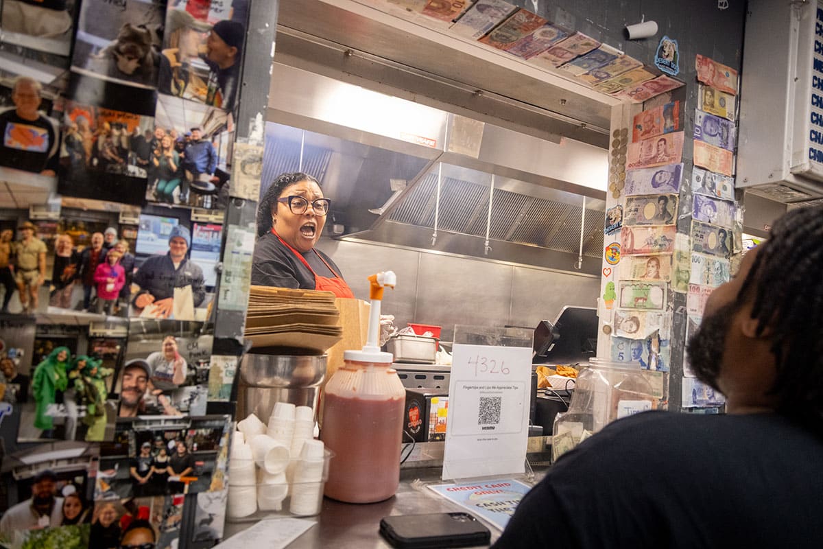 Roberta “Poochie” Jackson behind the counter conversing with an ordering customer
