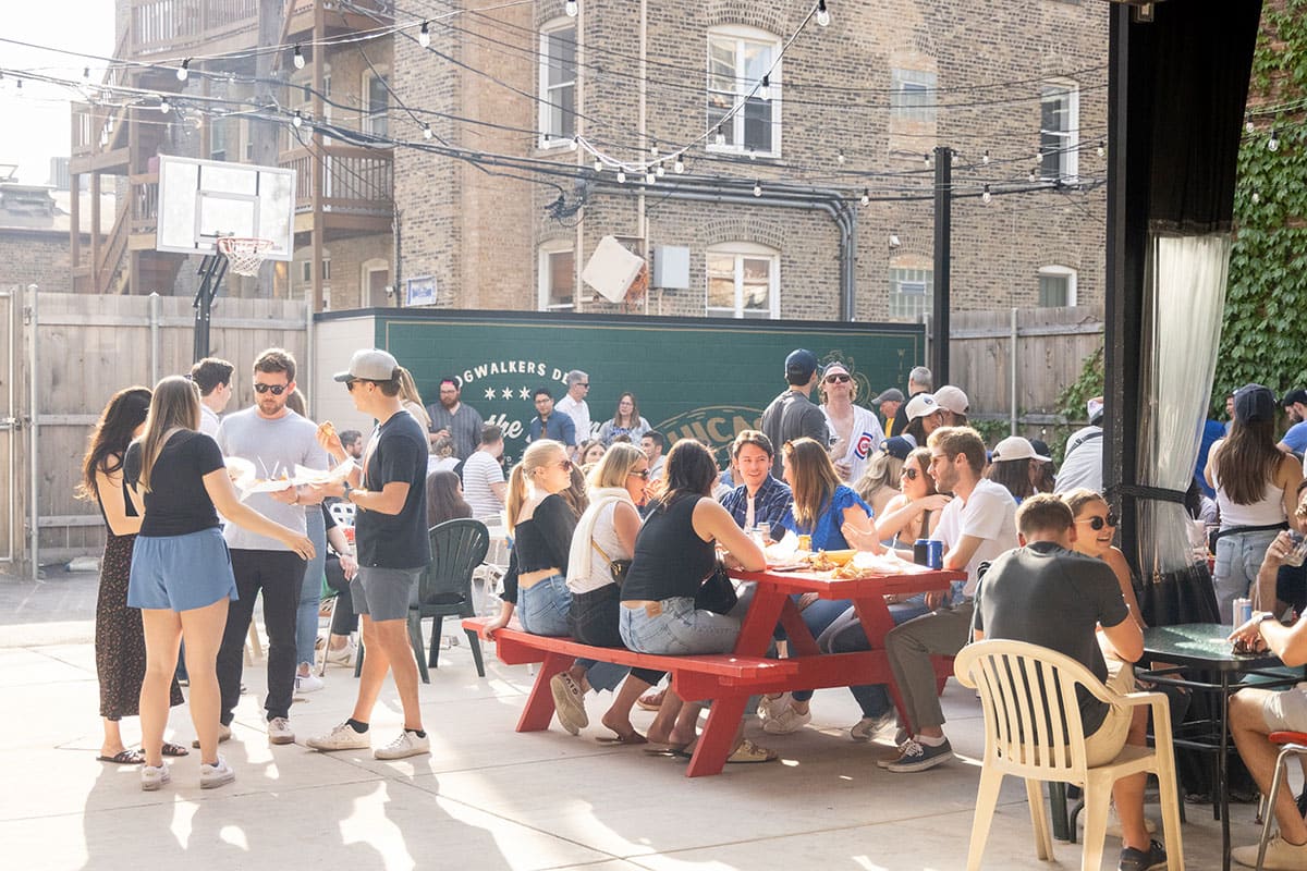 People stand and sit at picnic tables in the new patio