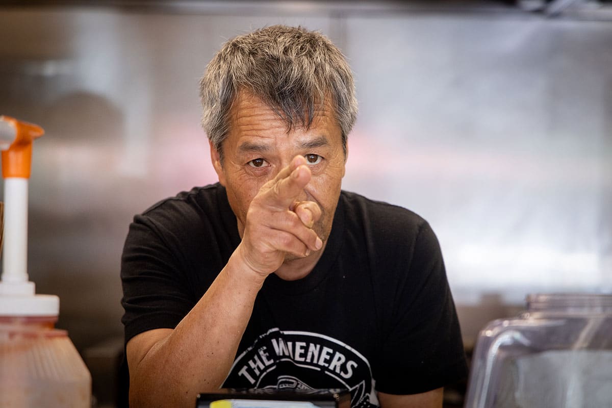 Manuel Murillo pointing two fingers out of the ordering window at customers