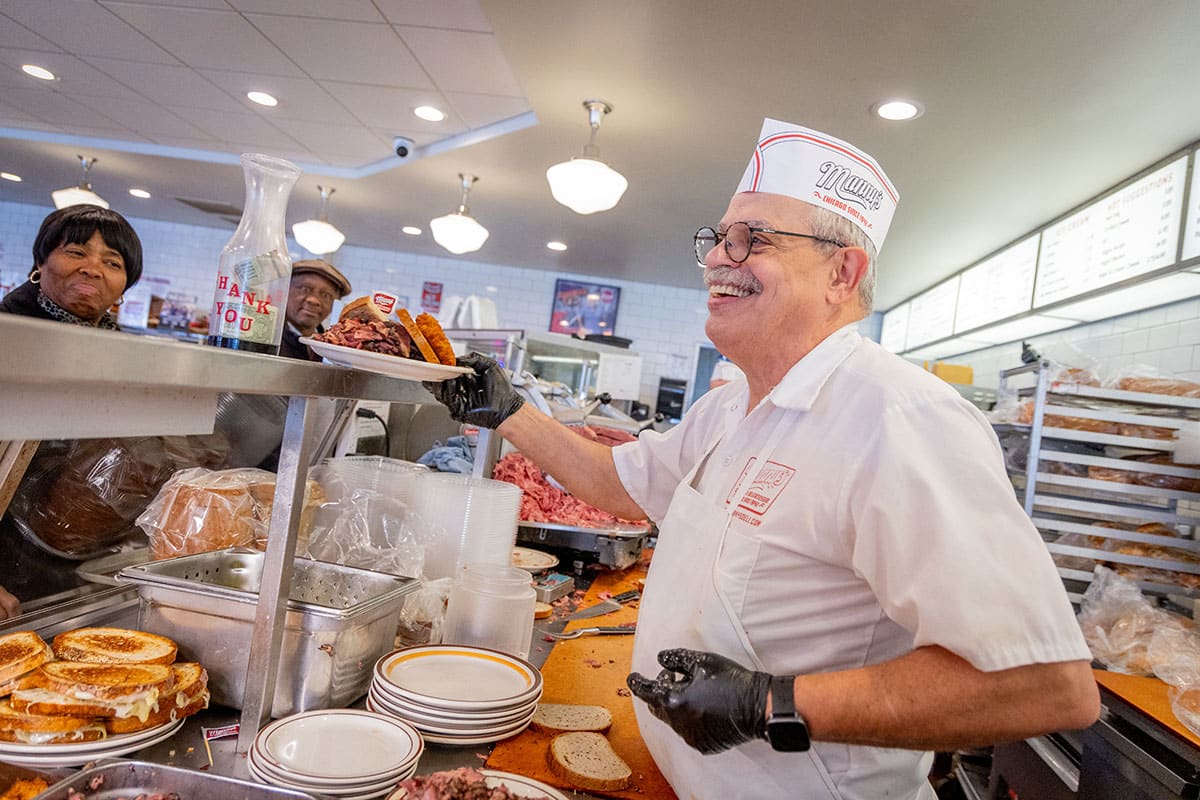 Smiling chef in a diner serving food at the counter, vibrant atmosphere and colorful dishes.