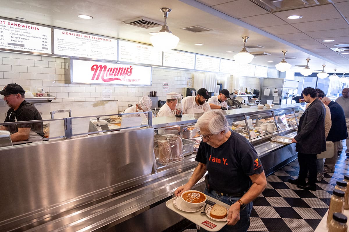 A busy diner with staff serving food, and customers waiting at the counter.