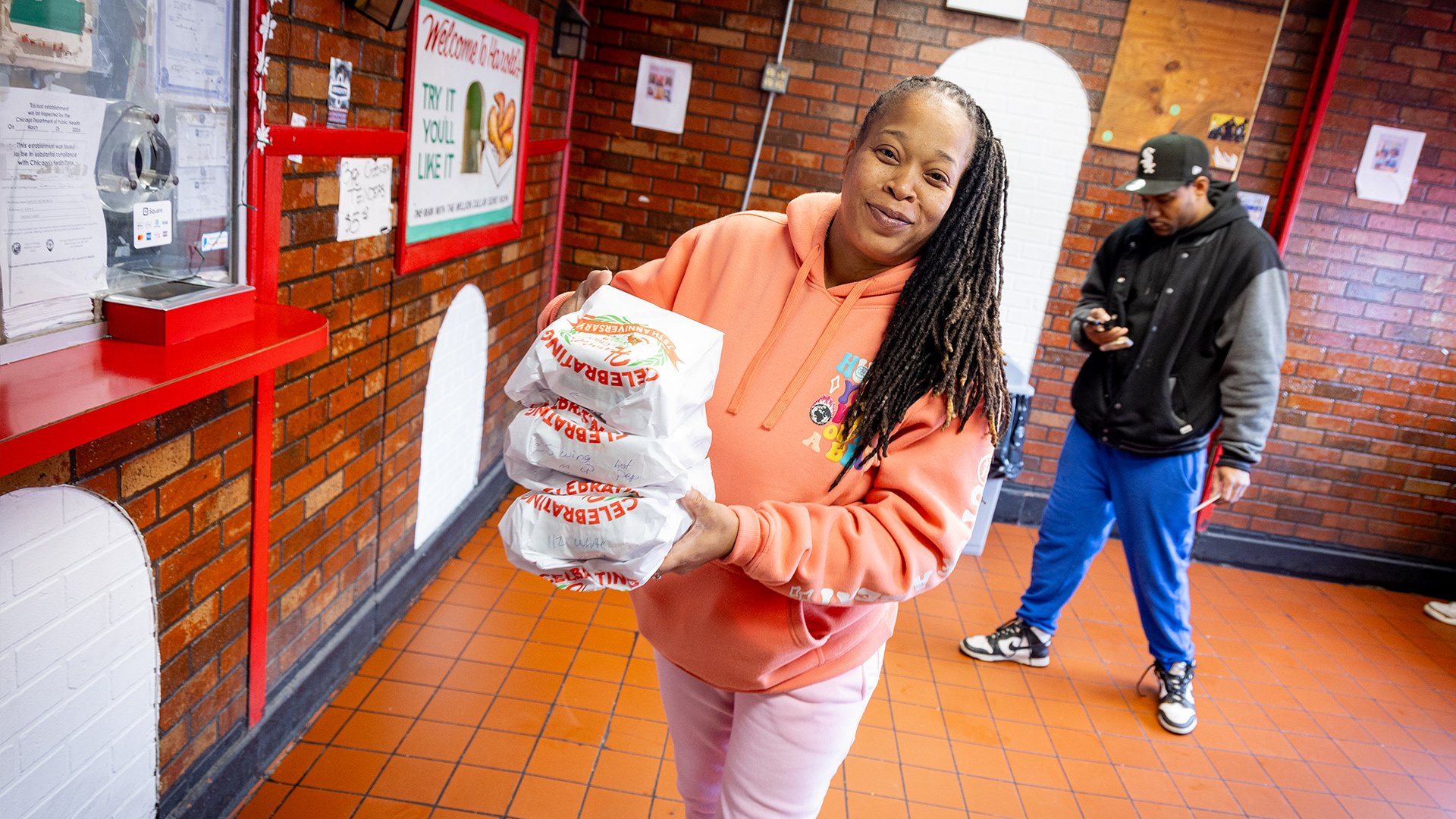 A patron picking up three orders of Harold's