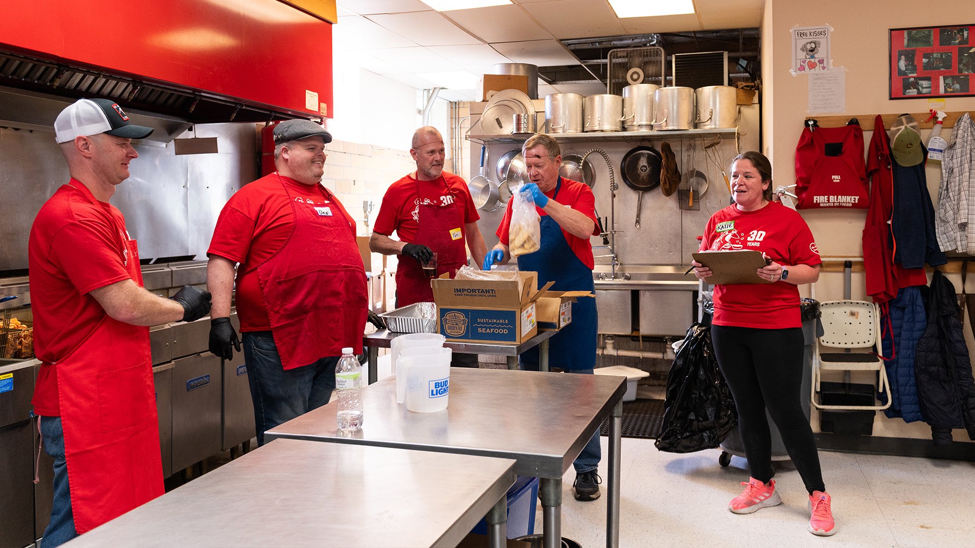 Katie Conwell standing in the kitchen with a clipboard among other employees