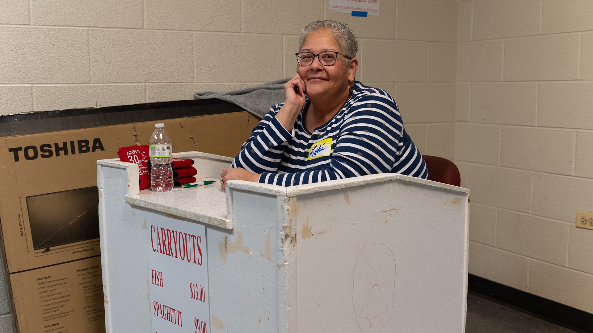 Lydia Mahoney smiling sitting at the carryout desk