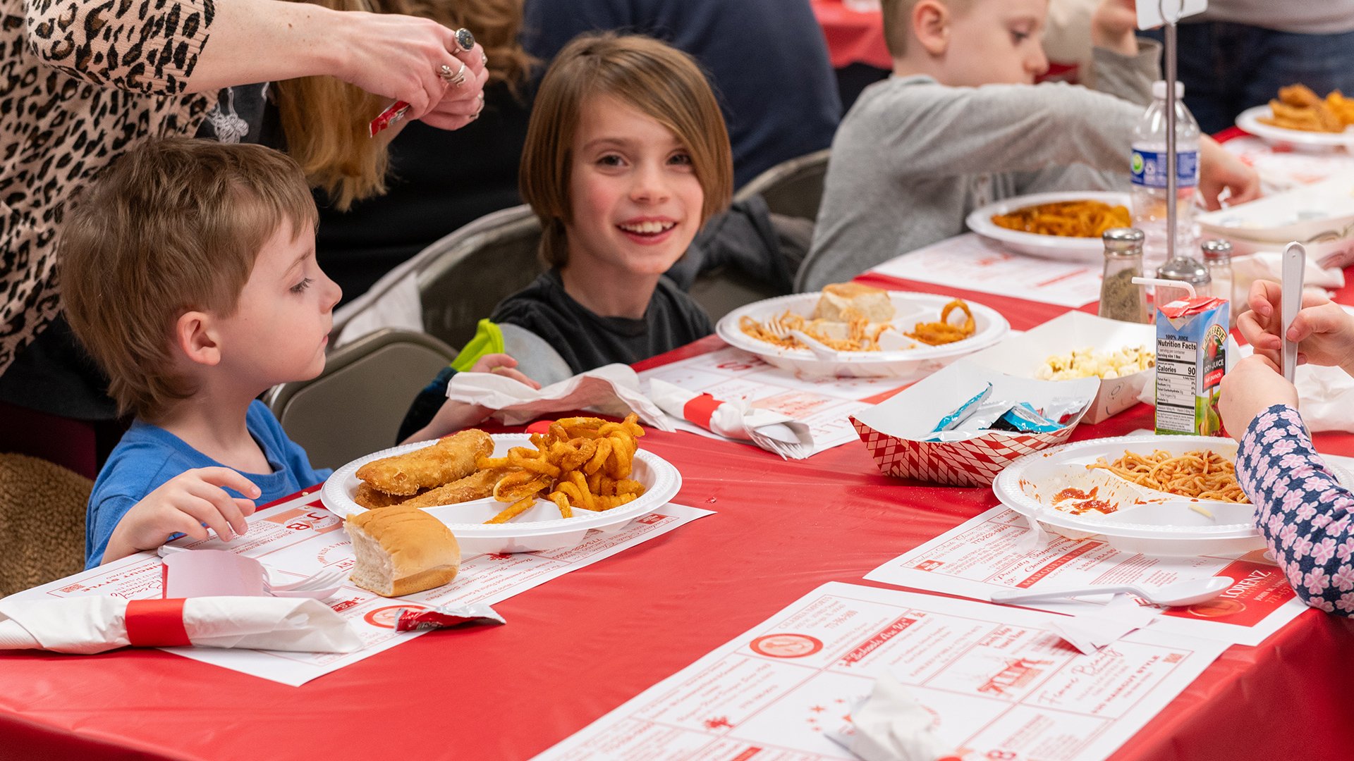 A young boy smiling at a cafeteria table