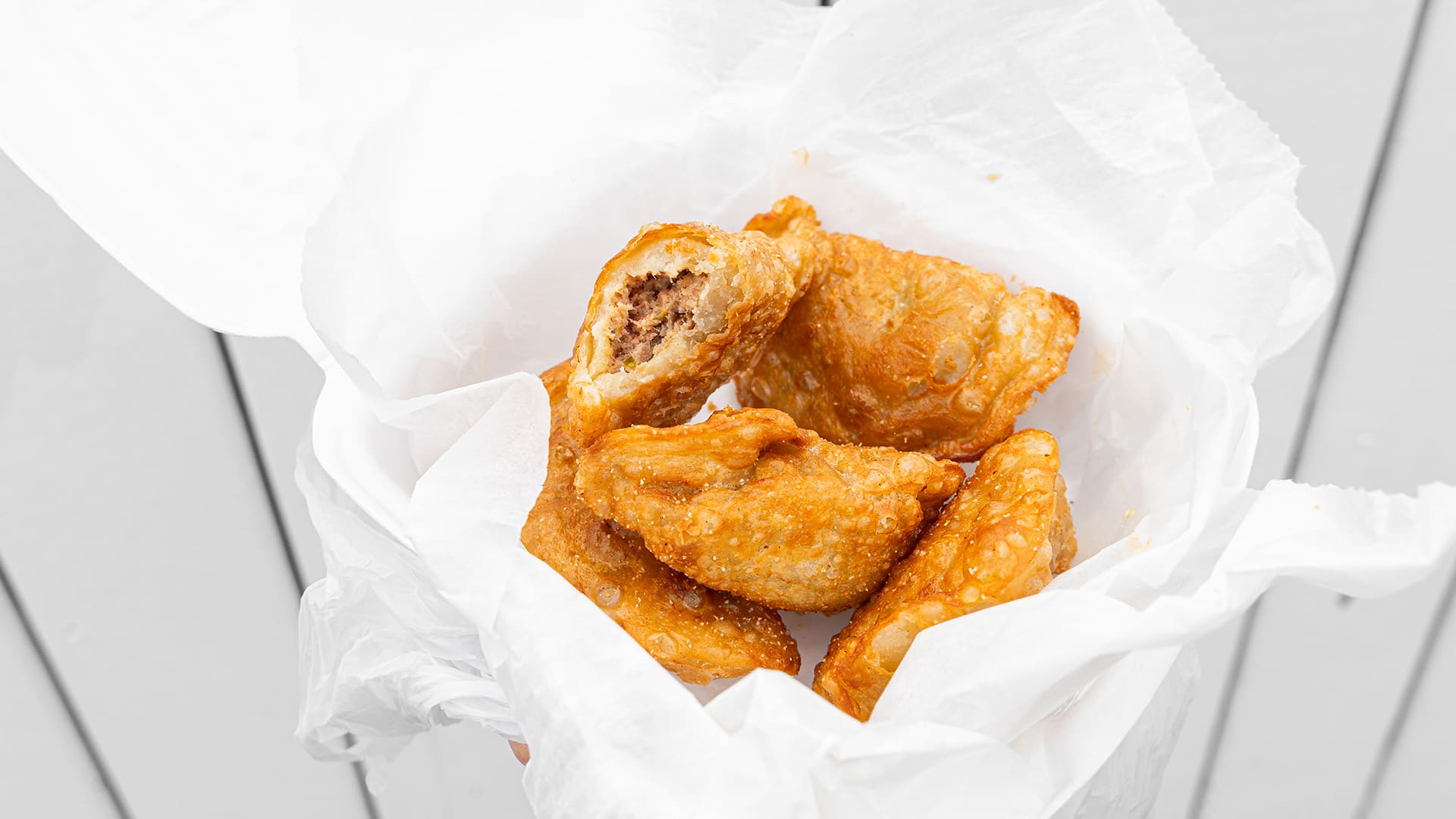 Deep fried pierogi, with one opened to show the filling.