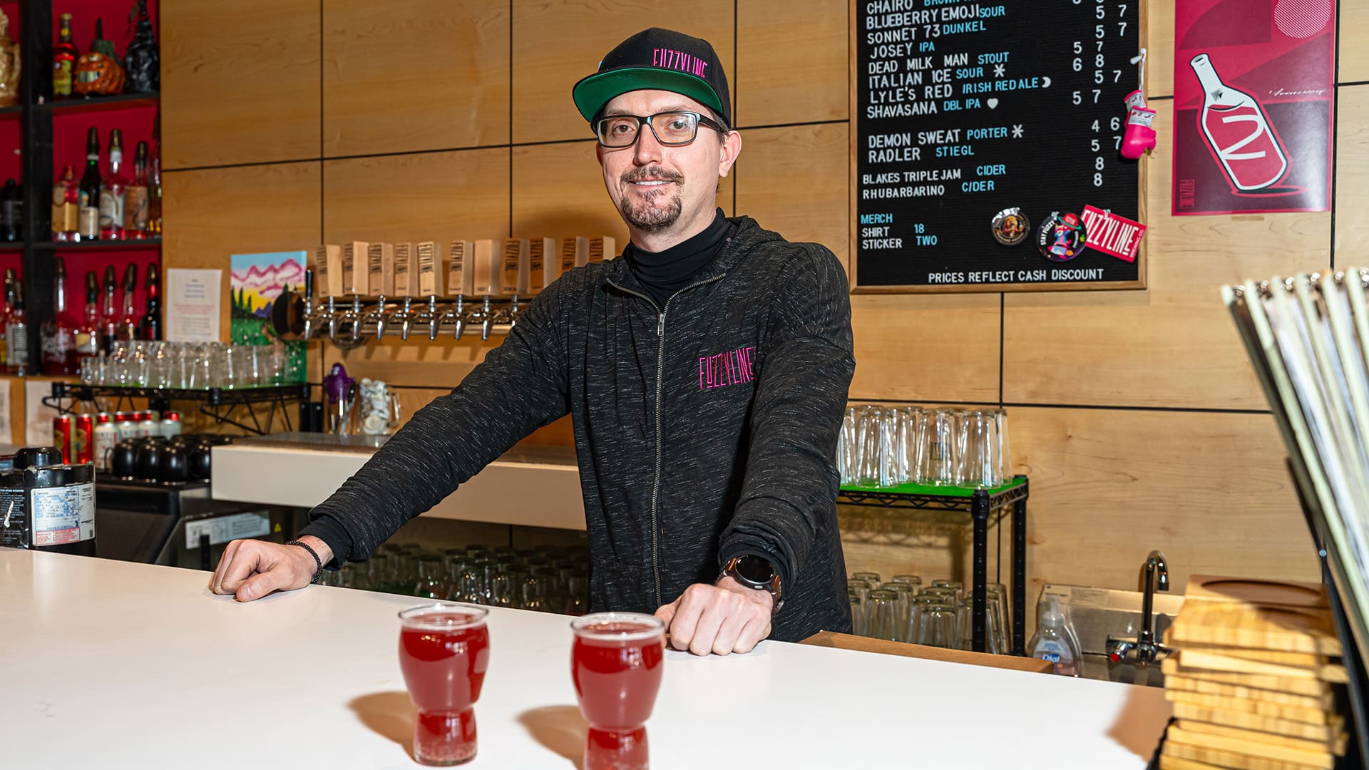 Alex Robertson stands behind the bar with two glasses of beer.