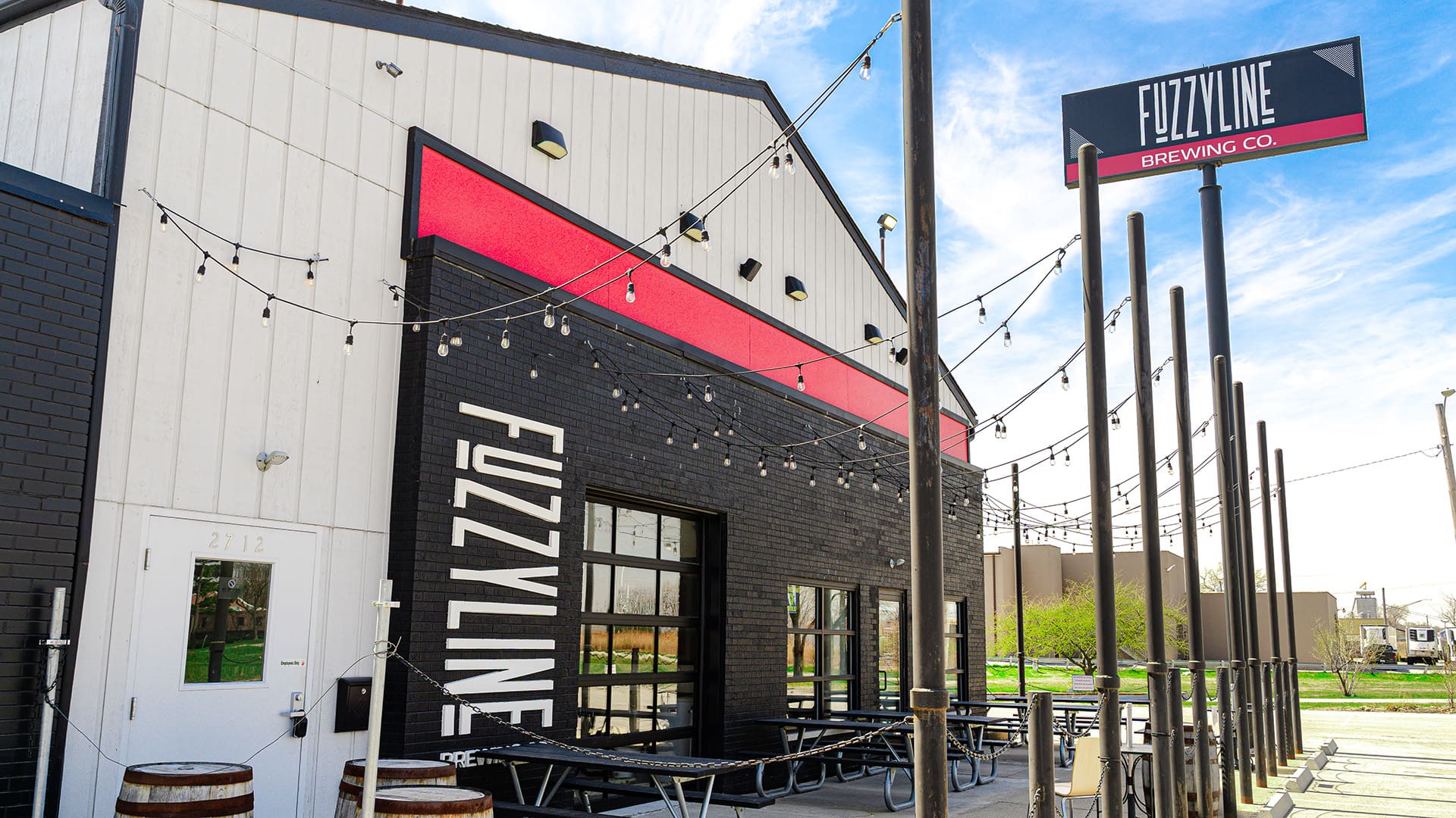 The exterior of Fuzzyline Brewery with barrels, picknic tables and lights strung up