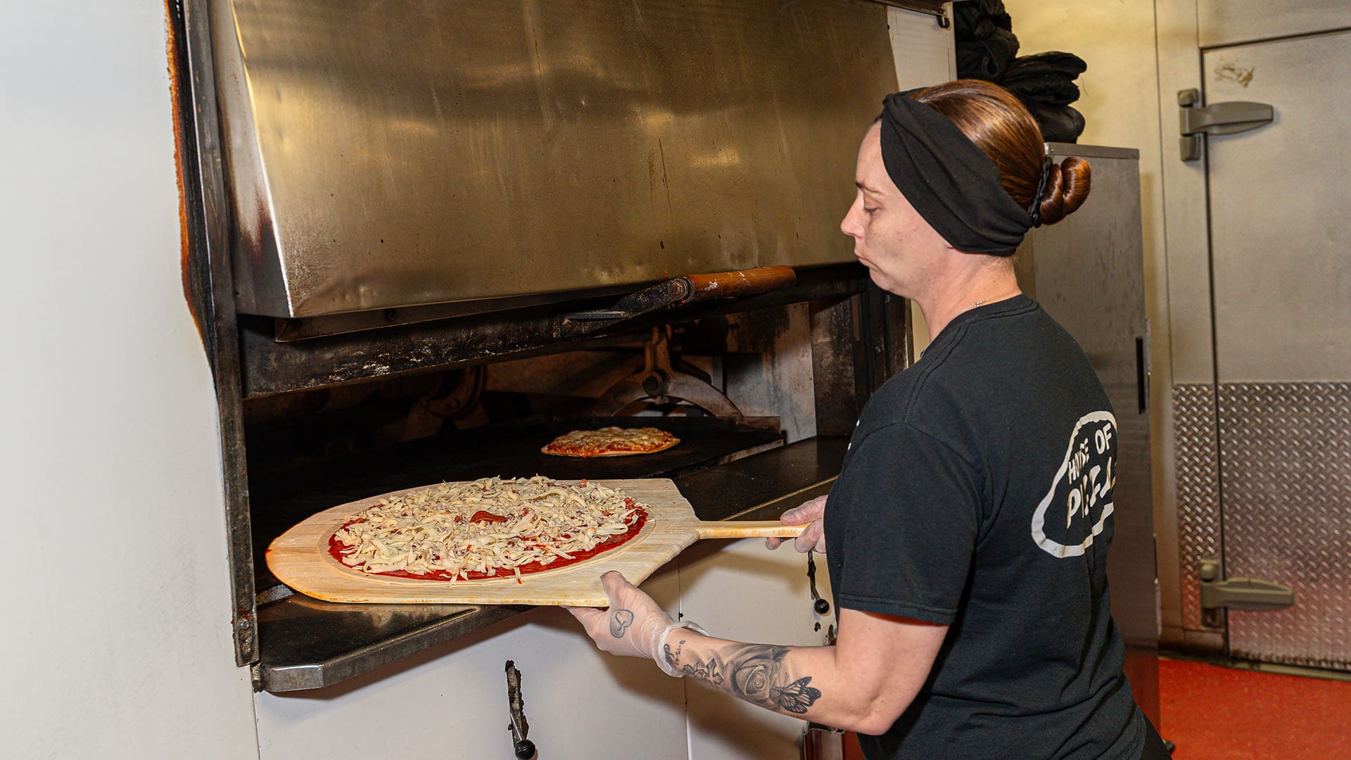 A chef moves a pizza into the oven