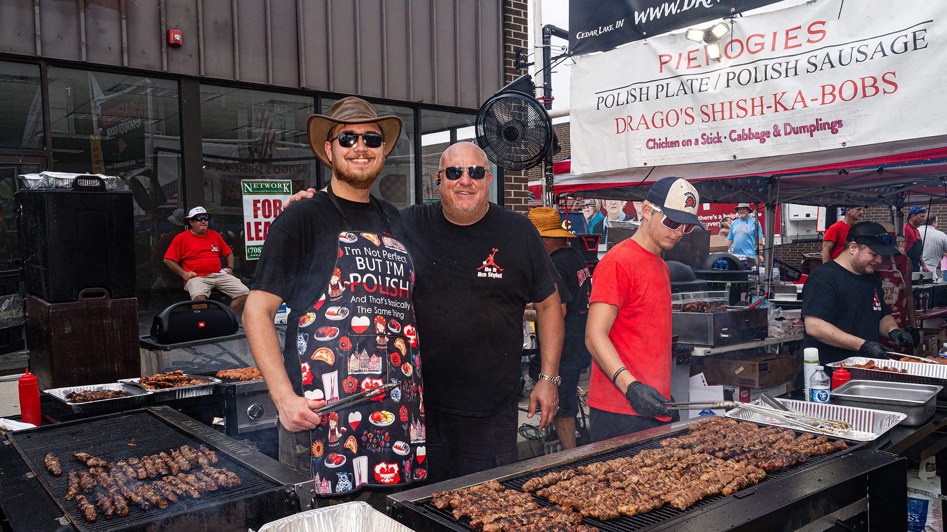 Workers pose behind grills of shish-ka-bobs to get their photo taken