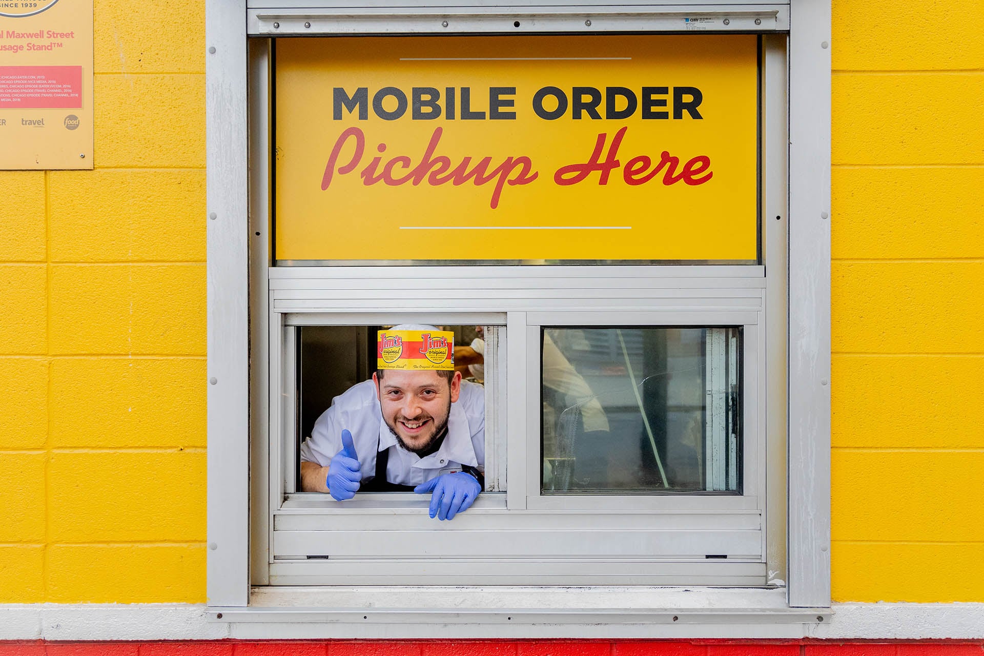 Worker giving a thumbs up from the mobile order pickup window at Jim’s Original