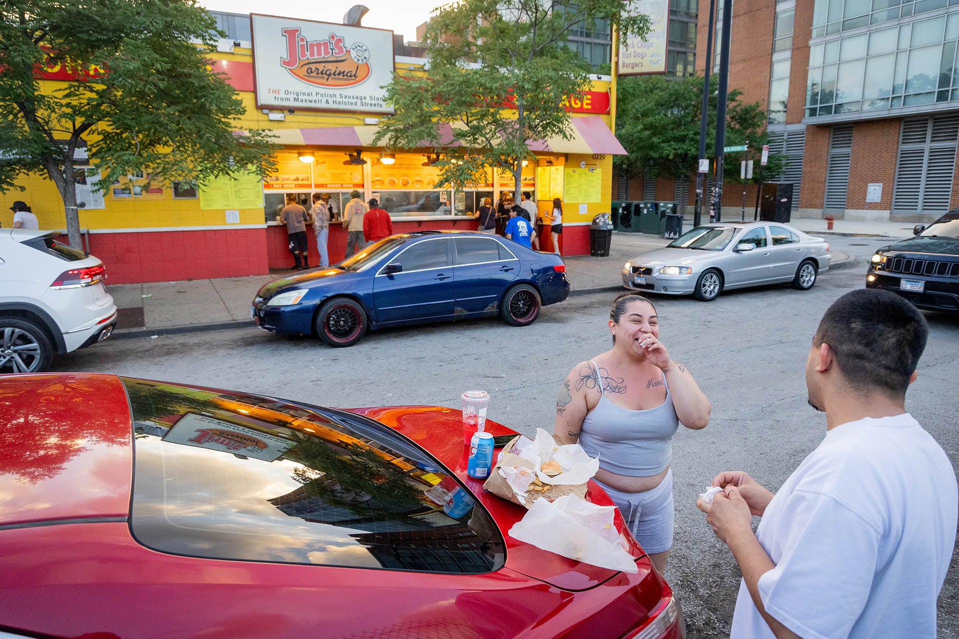 Two customers eating off the trunk of a car parked across from Jim’s Original