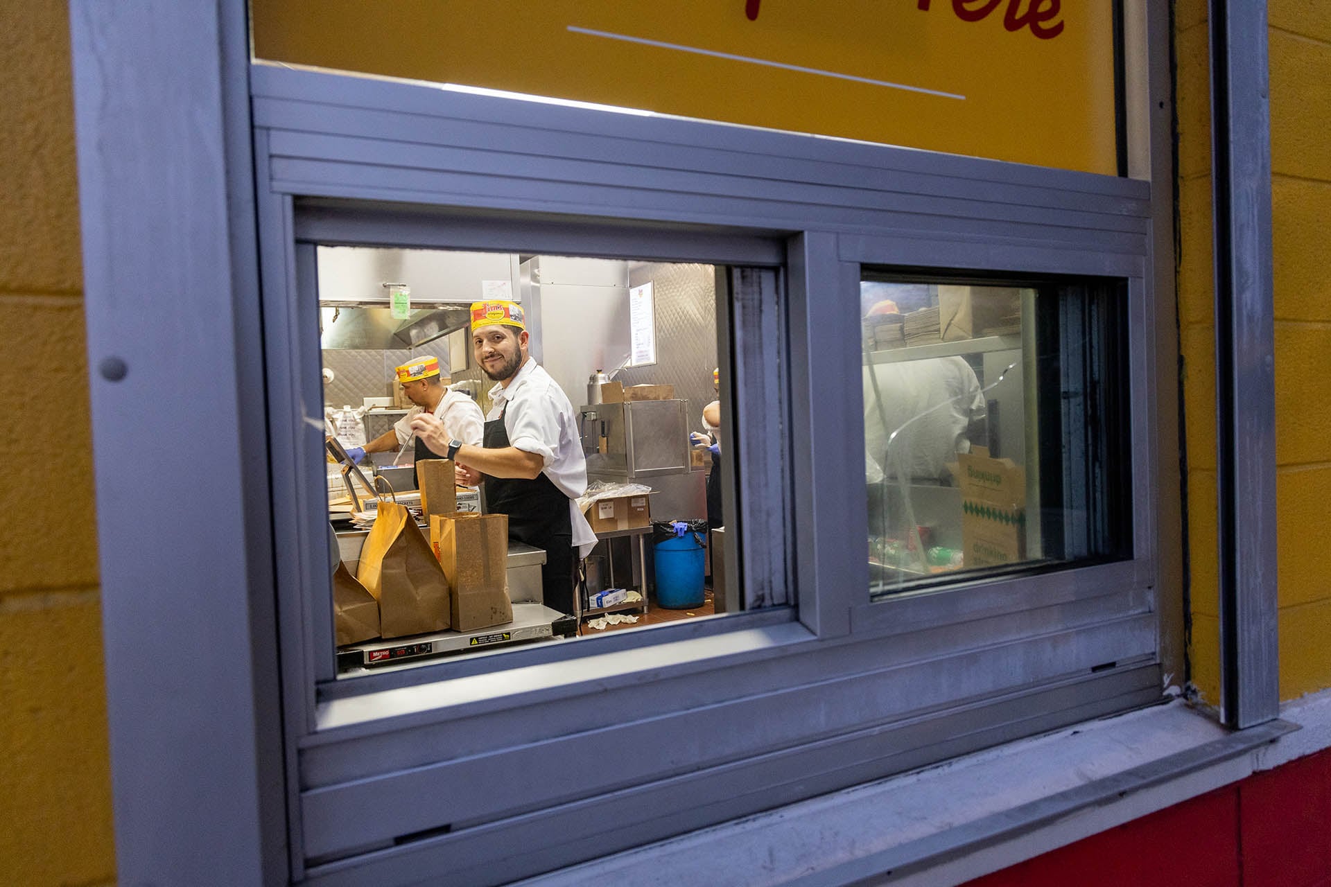 Workers visible through the window of Jim’s Original at night