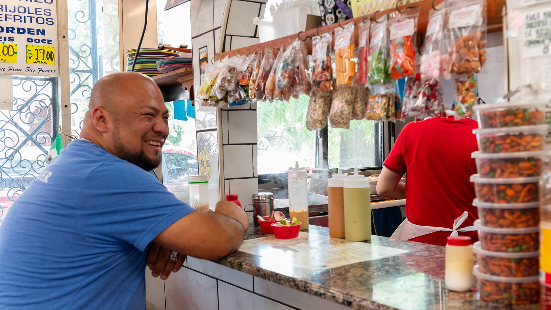 A man sits smiling at a counter with merchandise on display