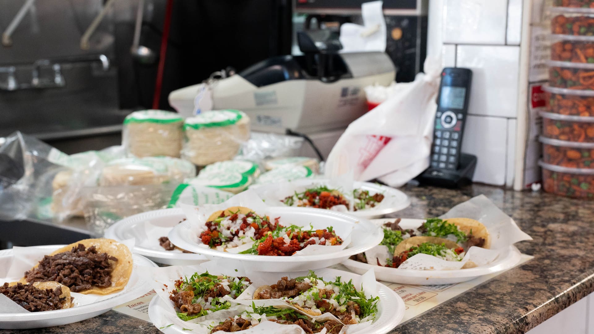 Styrofoam plates of tacos sit on a counter