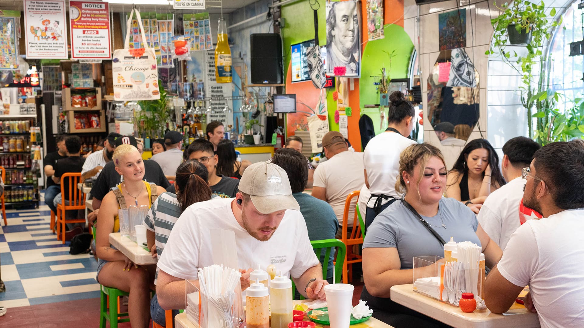 People sit at tables inside a store eating tacos