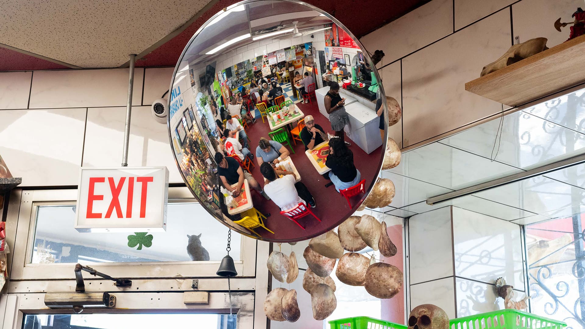 A view of a store full of tables of customers seen in a reflective mirror