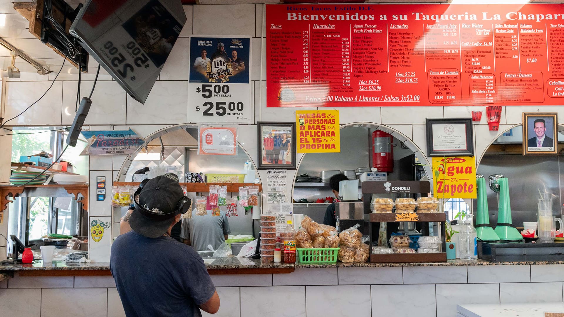 A person stands at a counter in a restaurant with his back to the camera
