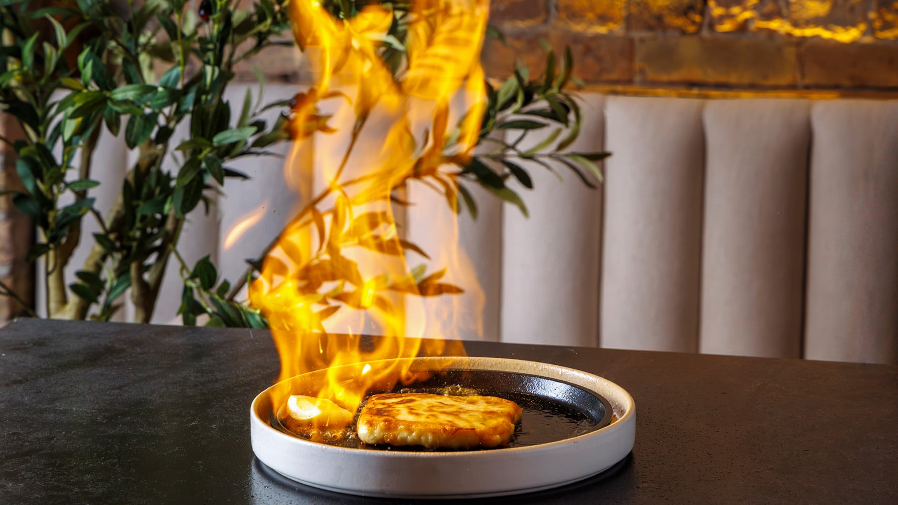 A plate with a flaming square of cheese on it