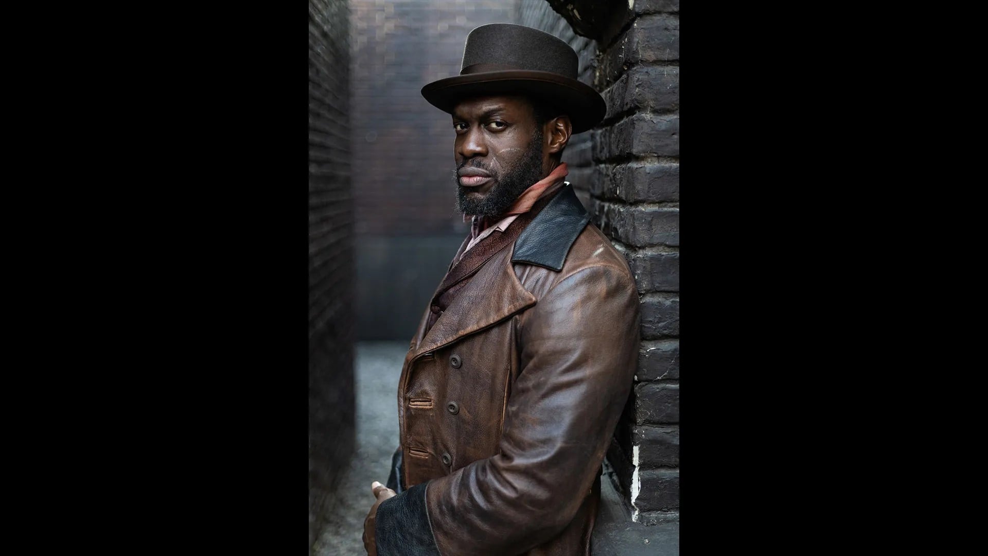 Moses poses in a leather coat in an alley