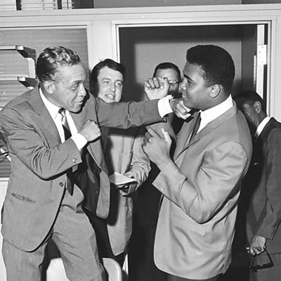 Jessie Howard climbs a chair to spar with heavyweight champ Muhammad Ali in Chicago, Illinois on July 16, 1965. Photo: ST-50000284-0001, Chicago Sun-Times collection, Chicago History Museum