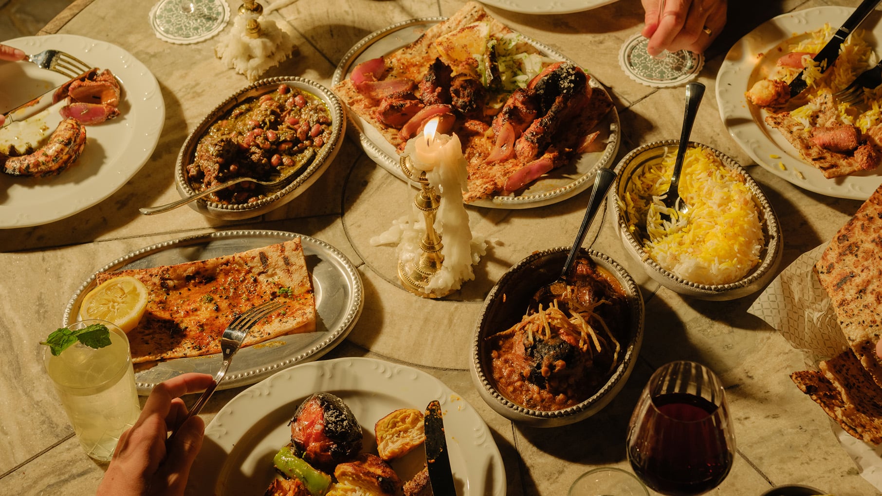A spread of food on a table with melty candles in moody lighting