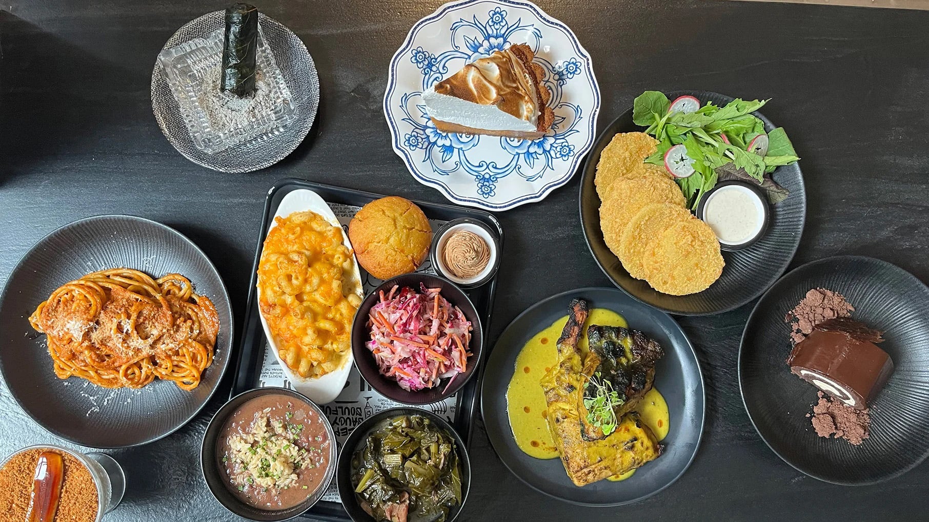A spread of barbecue, pasta, pie, and other food on plates seen from above