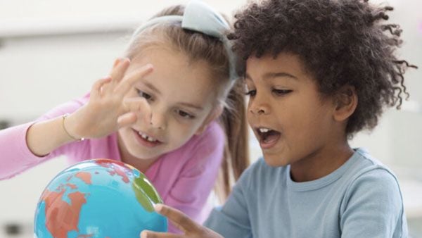 Two kids looking at a globe.