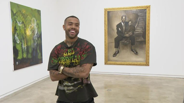 Chicago rapper Vic Mensa standing before two paintings.