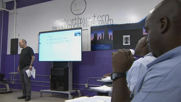 Men at the Stateville Correctional Center sit in a classroom with a "Northwestern Prison Education Program" emblem on the wall. (WTTW News)
