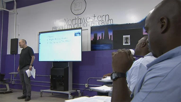 (WTTW News) Men at the Stateville Correctional Center sit in a classroom with a "Northwestern Prison Education Program" emblem on the wall. (WTTW News)