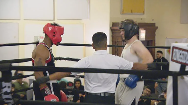 Two young men and a referee in a boxing ring