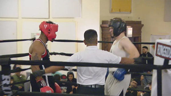 (WTTW News) Two young men and a referee in a boxing ring