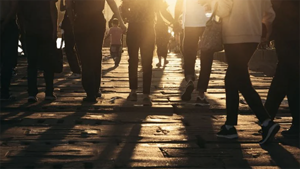 People walking down the street backlit by the sun