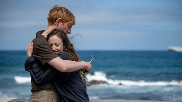 Alice and Jack hug in front of the ocean