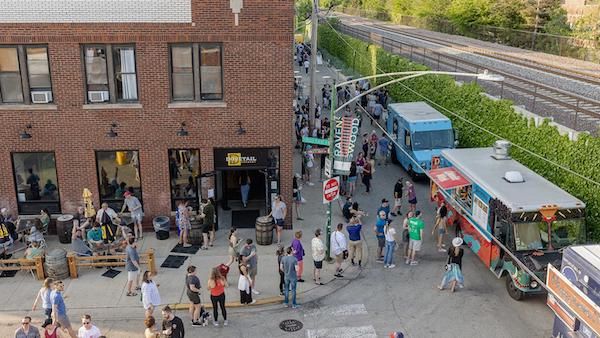 An aerial view of people milling about outside around food trucks