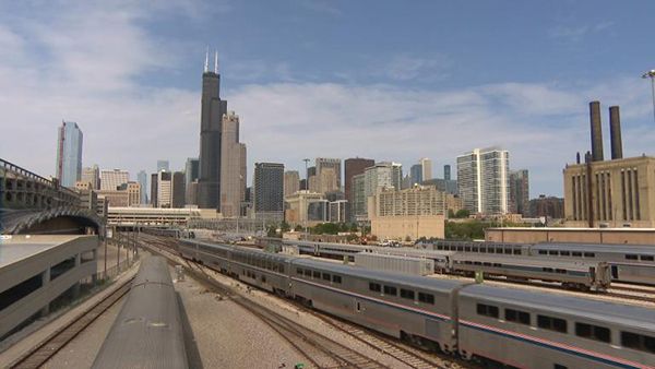An Amtrak train on the tracks with the Chicago skyline in the background