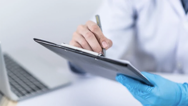 A doctor's hands taking notes on a clipboard 