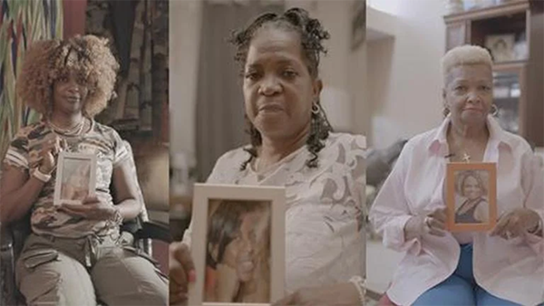 Three women holding up photographs of their loved ones