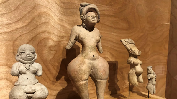 Four stone fertility goddesses against a wood background