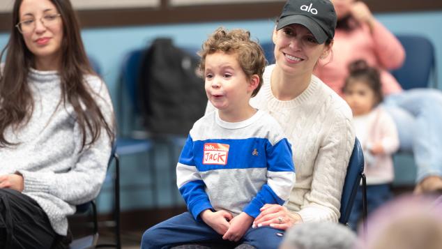 Toddler sits on mother's lap smiling at WTTW Kids Learn & Play event