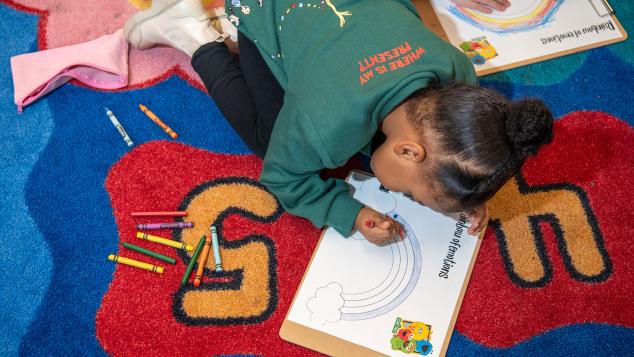 A young child colors in a rainbow at a WTTW Kids Learn & Play event.