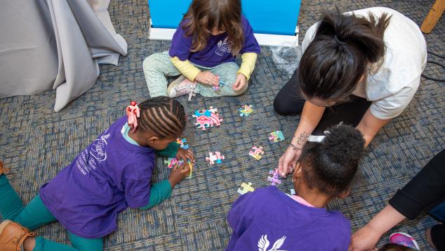 A small group of toddlers put a puzzle together
