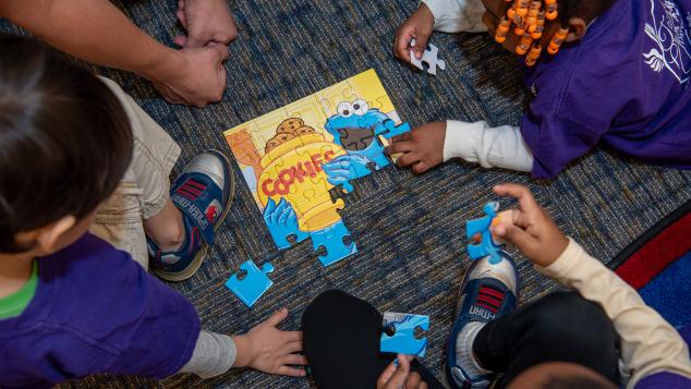 A small group of toddlers put a puzzle together