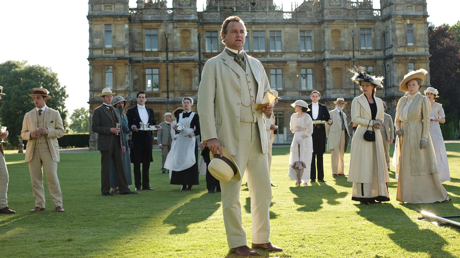 A garden party at Downton Abbey with Robert, the staff, and more standing on the lawn