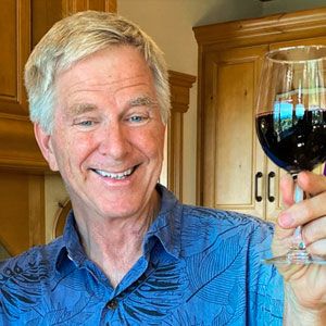 Rick Steves toasting with red wine.