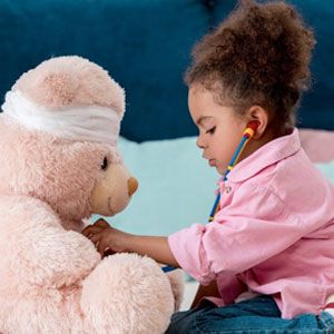 Child playing doctor with teddy bear.