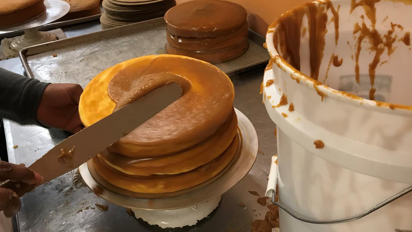 Frosting a carmel cake at Brown Sugar Bakery